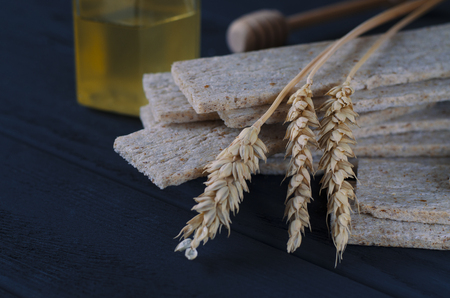 Healthy food. Air dietetic loaves lie on a dark wooden table on a dark background next to the ears of wheat and honeyの写真素材