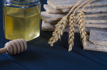 Healthy food. Air dietetic loaves lie on a dark wooden table on a dark background next to the ears of wheat and honeyの写真素材