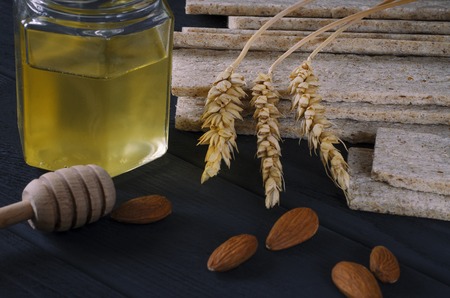 Healthy food. Air dietetic loaves lie on a dark wooden table on a dark background next to the ears of wheat and honeyの写真素材