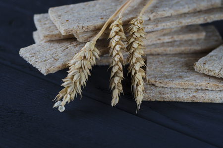 Healthy food. Air dietetic loaves lie on a dark wooden table on a dark background next to the ears of wheat and honey.の写真素材