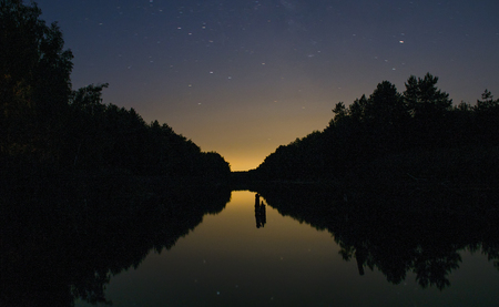 Bright sunset amid dark skies above the River in the forestの写真素材