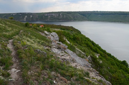 The huge river Dniester flows between high steep hills covered with spring lush green grass against the blue skyの写真素材