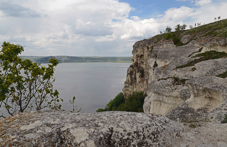 The huge river Dniester flows between high steep hills covered with spring lush green grass against the blue skyの写真素材
