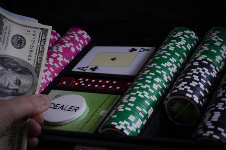 On the black table lie poker chips, cards and a dealer chip. Man's hand holds cardsの写真素材