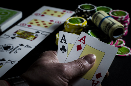 On the black table lie poker chips, cards and a dealer chip. Man's hand holds cardsの写真素材