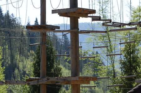 Wooden pillars and hanging ropes of a rope park on the background of green forest in the Carpathiansの写真素材