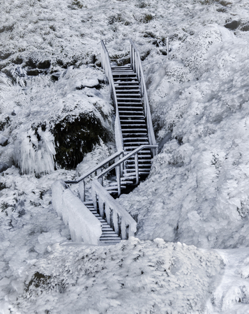 Wooden staircase frozen in ice, covered with icicles against a frozen lava field covered with ice and snow. Icelandの写真素材