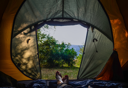 Female legs in a green tent against the sky and mountains. Campingの写真素材