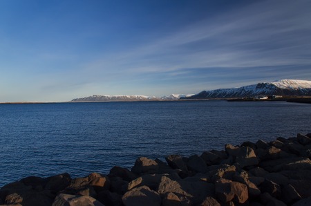Bright Reykjavik against the backdrop of zasnezhenyh mountain peaks. View from the Atlantic Oceanの写真素材