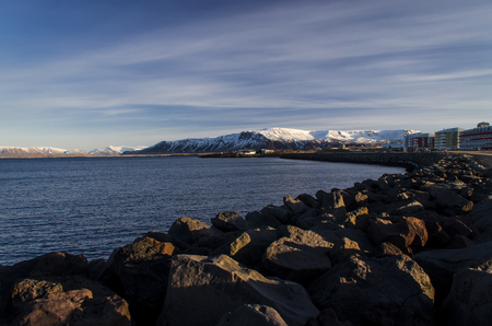 Bright Reykjavik against the backdrop of zasnezhenyh mountain peaks. View from the Atlantic Oceanの写真素材