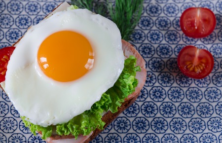 good morning. Delicious breakfast with Sandwich with egg, ham, cheese, toast and salad leaves lies on a plate with tomato and dillの写真素材