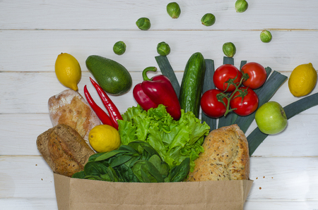 Top view paper bag of different fresh health food on white wooden background. Top view. Flat layの写真素材