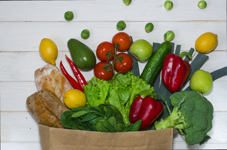 Top view paper bag of different fresh health food on white wooden background. Top view. Flat layの写真素材