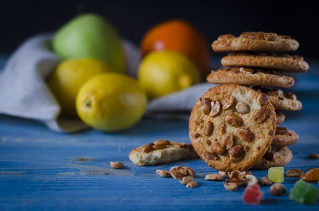 Round orange biscuits with colorful candied fruits and a slice of juicy orange lying on a wooden table. Closeupの写真素材