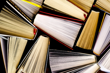 Lots of colourful thick open books stand on a dark background. ready to readの写真素材