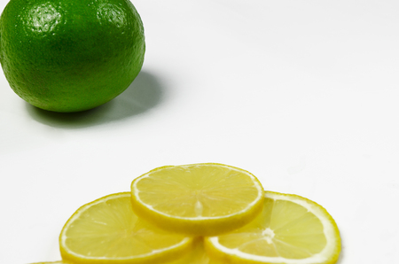 Thinly sliced wedges of lemon and lime green are lying on a white background with copy space top viewの写真素材