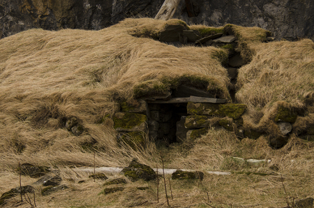 Old stone house destroyed ancient Viking overgrown with yellow dry grass in Icelandの写真素材