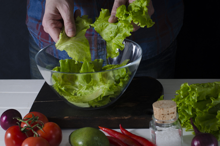 Man cooking green detox salad of romaine lettuce. Healthy food conceptの写真素材