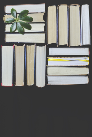 Many multicolored thick open books stand on a dark background. On the books are old round glasses and an open notebook with a pencil. ready to readの写真素材