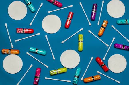 Concept of the menstrual period. Women's Protection of Hygiene. Multicolored flower swabs with colorful petals on a blue background. Hygiene products: round white cotton pads and cotton swabs are on colored background. Top view, flat layの写真素材