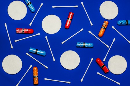 Concept of the menstrual period. Women's Protection of Hygiene. Multicolored flower swabs with colorful petals on a blue background. Hygiene products: round white cotton pads and cotton swabs are on colored background. Top view, flat layの写真素材
