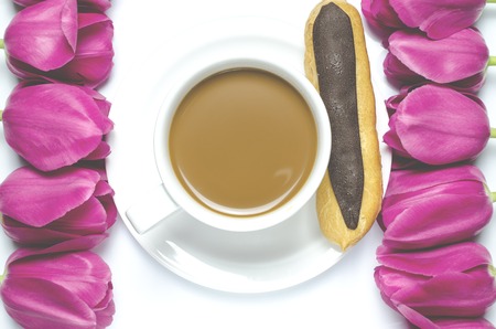Pink tulips lay on a white background near the white coffee cup, which stands on a white saucer. closeupの写真素材