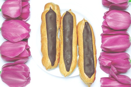 Dessert. Sweet biscuits with chocolate are on a white background next to colorful tulips. Closeupの写真素材