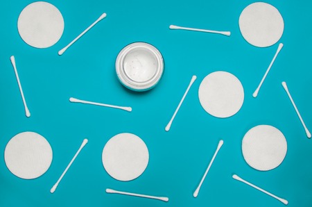 Hygiene products: round white cotton pads and cotton swabs are on colored background. Top view, flat...