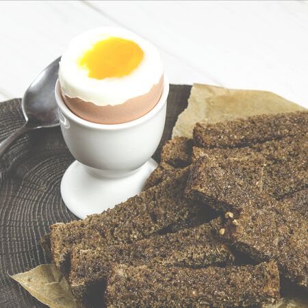Healthy food. English breakfast with boiled egg and croutons on a white wood background