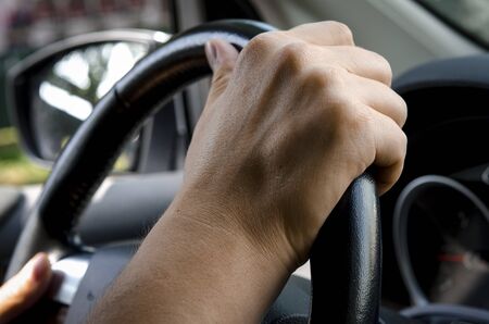 Close up shot of a man's hands holding a car's steering wheel
