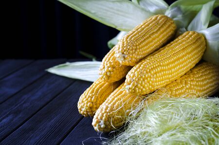 Fresh juicy yellow corn bonduel with green leaves lies on the wooden table. Healthy foodの写真素材