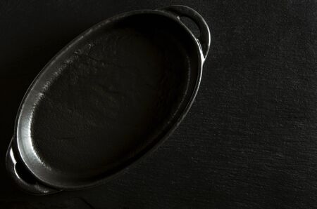 Black oval form for baking stands on a black background of stone. Close-upの写真素材