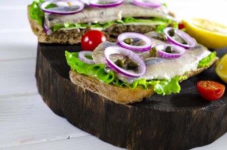 Herring fillet with salt, pepper, herbs, onion and lemon on black plate on white background. top view. healthy foodの写真素材