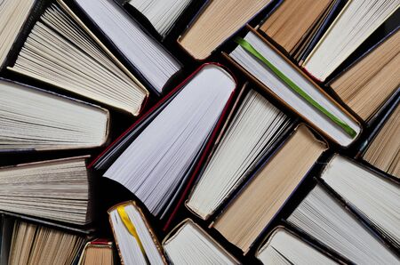 Lots of colourful thick open books stand on a dark background. ready to readの写真素材