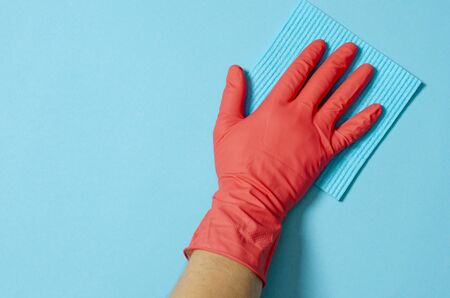 Employee hand in rubber protective glove with micro fiber cloth wiping wall from dust. Commercial...