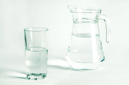 Pure clear water in a glass glass and glass jug stands on a white background. isolatedの写真素材