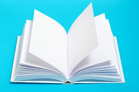 Mockup of opened blank square ctalogue at white design paper background. An open white book rests on...