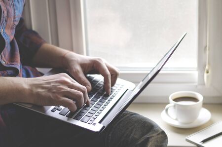 Man using laptop in home office. Male hands typing on keyboard. Business work on laptop