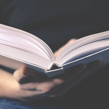 Men's hands hold a white book. Close-up