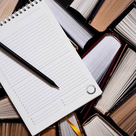 Lots of colourful thick open books stand on a dark background. ready to read