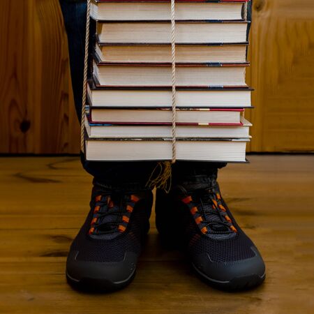 A man holds many multi-colored books tied with a rope
