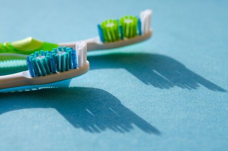 New multicolored toothbrushes with sharp shadows lie on a blue background. Close-upの写真素材