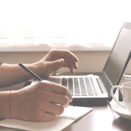 Freelancer works in the home office sitting at the desk near the window. Open laptop with blank...