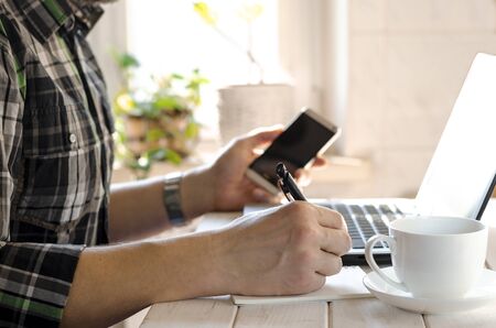 Freelancer works in the home office sitting at the desk near the windowの写真素材