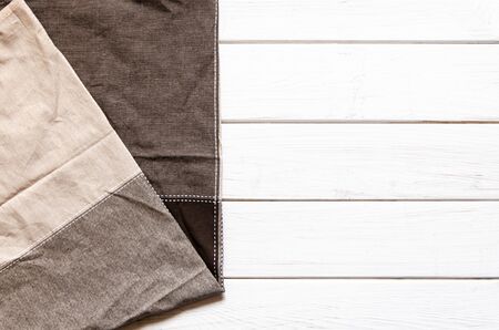 A multi-colored cloth napkin rests on a white wooden background. Top viewの写真素材