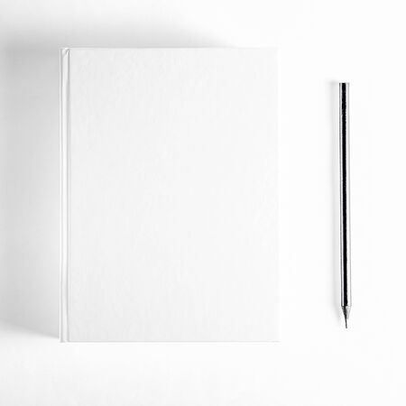 Mockup of closed blank square book and black pencil at white textured paper background. Hardcover Book Mock-Up - Dust Jacket. Wall Backgroundの写真素材