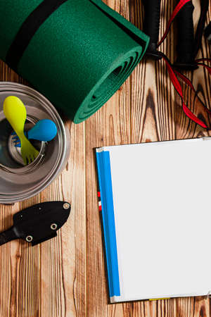 Travel content. Backpack, quad, sticks for Scandinavian walking and tourist utensils stand on a wooden backgroundの写真素材