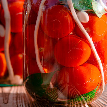 Autumn harvest of red tomatoes, horseradish and garlic in jars for preservation