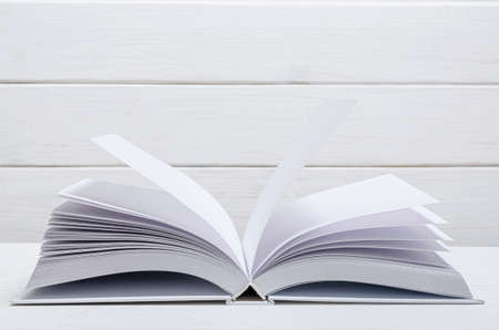 White new open book with clean empty pages lies on a wooded table