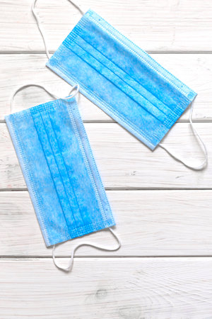 A pair of thin blue medical latex gloves and face shield on a white background. Disposable rubber...
